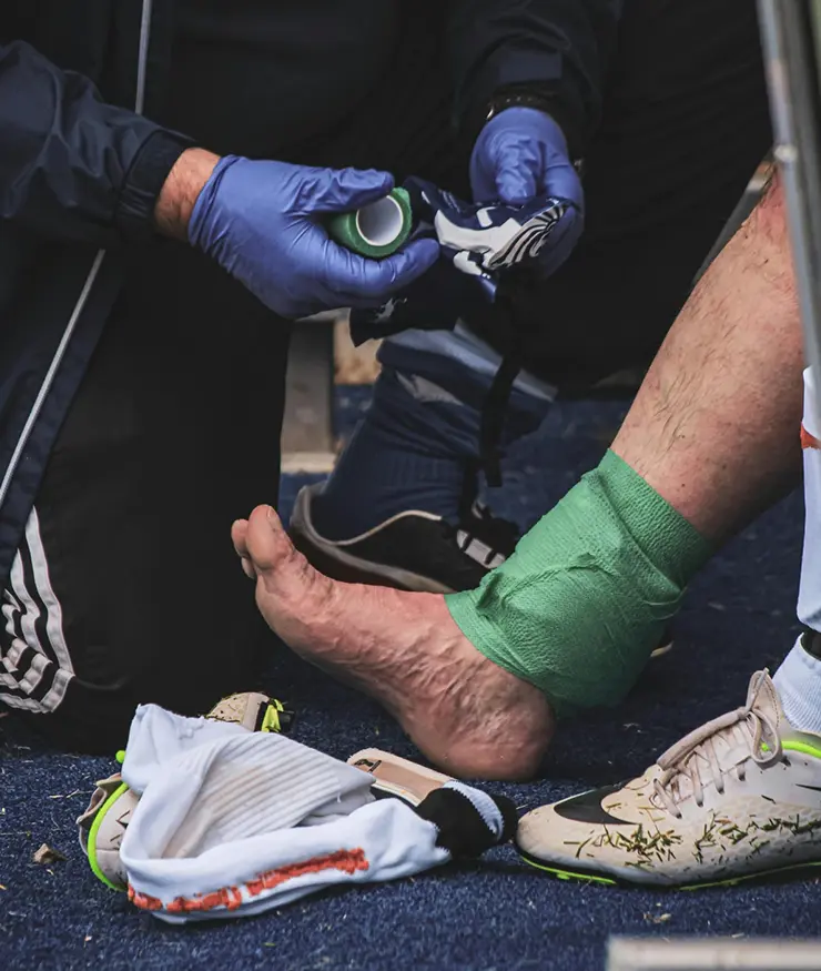 Lesión deportiva con aplicación de hielo y vendaje para estabilizar el tobillo