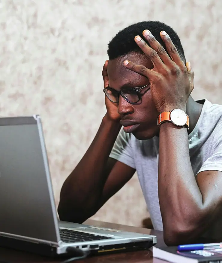 Hombre tomándose la cabeza, serio y preocupado en frente de una notebook.