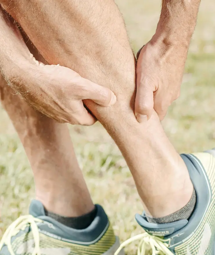 hombre sujetándose la pantorrilla izquierda en señal de dolor.