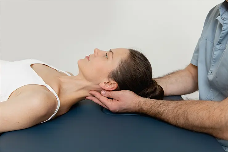 Mujer recibiendo un tratamiento osteopático, las manos del osteopata están apoyadas sobre el cuello de la mujer haciendo movimientos de manipulación en esa zona