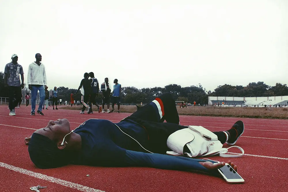 Una deportista descansando en el suelo de una pista de entrenamiento después de entrenar