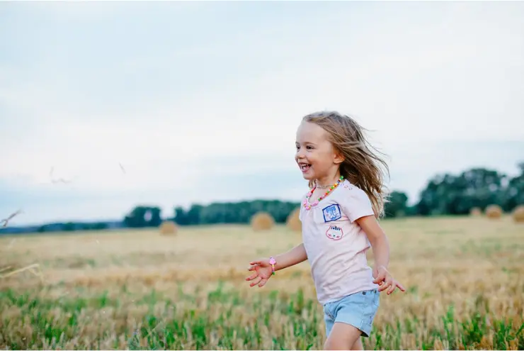 niña corriendo por el prado