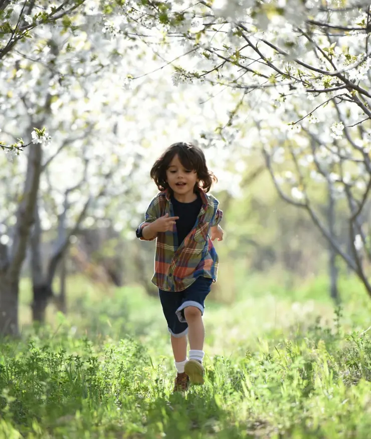 niño con camisa corriendo por la pradera