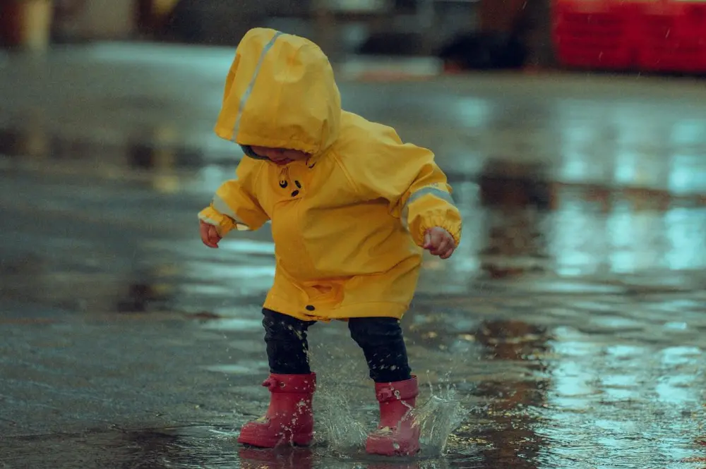 niño jugando bajo la lluvia con un piloto amarillo