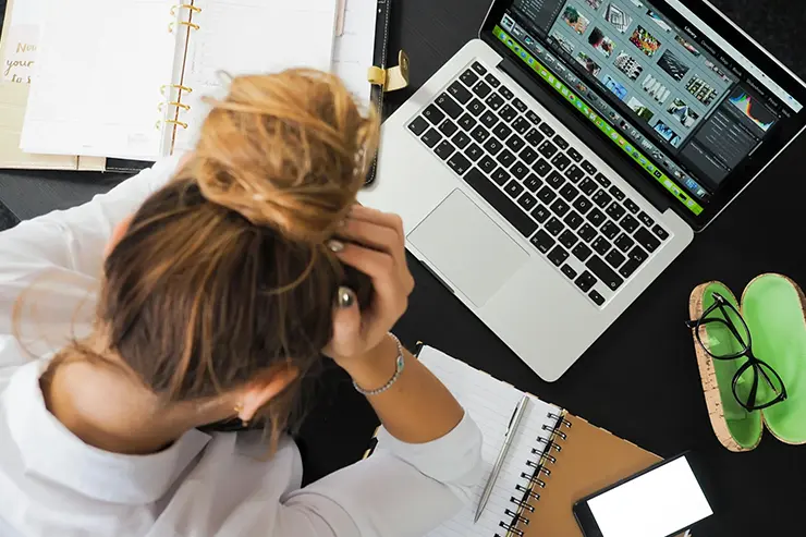 Una persona estresada frente a su computadora, trabajando desde su oficina