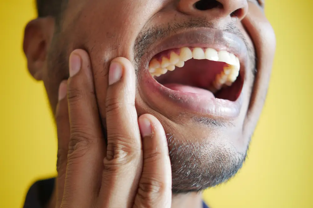 Una persona dolorida de la mandibula se toca la cara